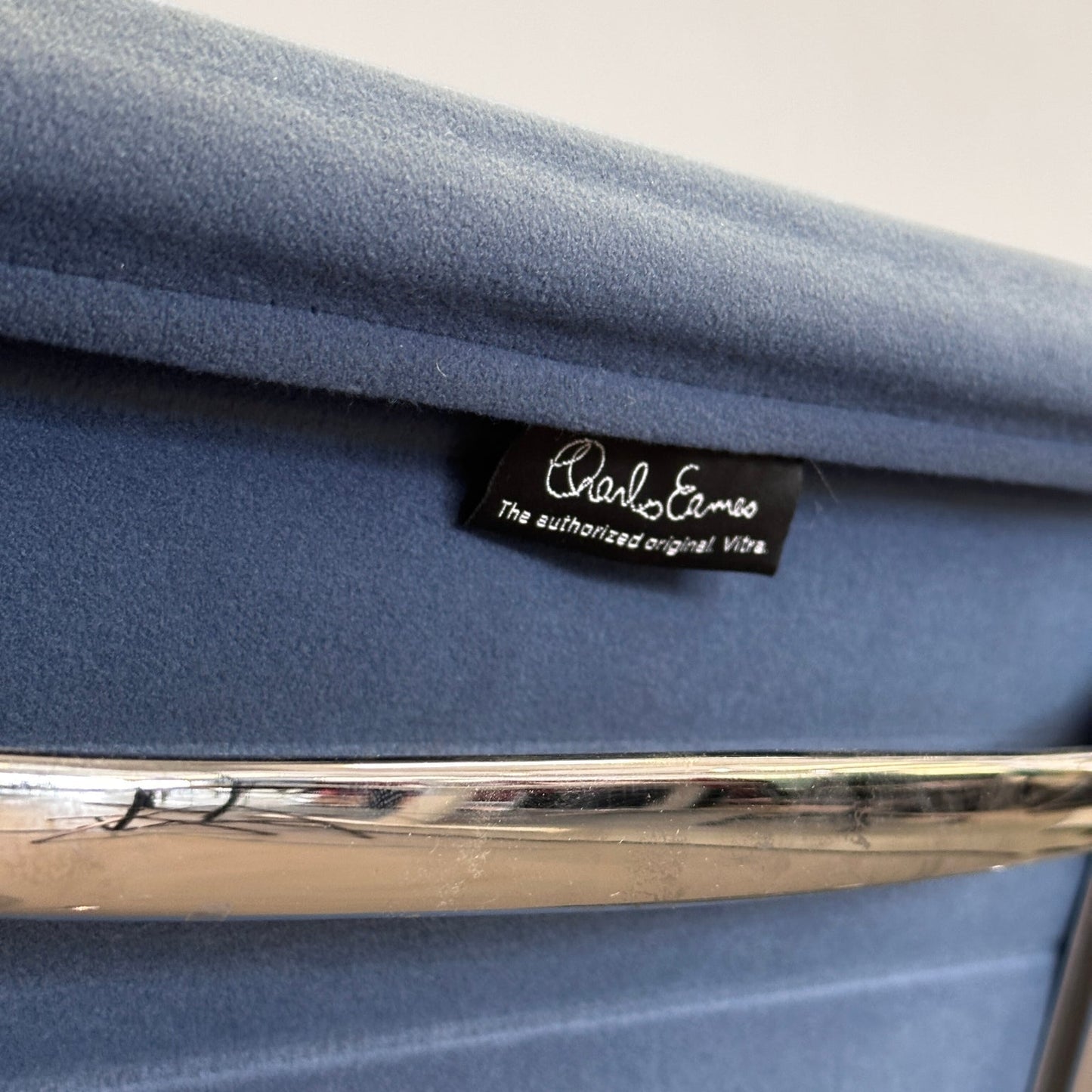 Vitra EA 108 Eames Alu Chair Detailaufnahme Velours petrolblau mit Chromgestell und Markenlabel
