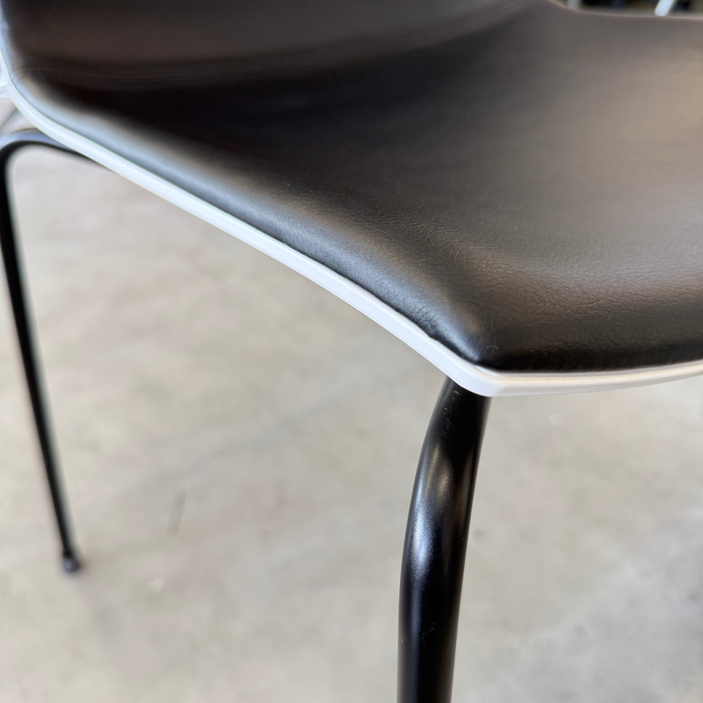 Arper Catifa 46 chair with black leather seat, white shell, and four-leg black metal frame