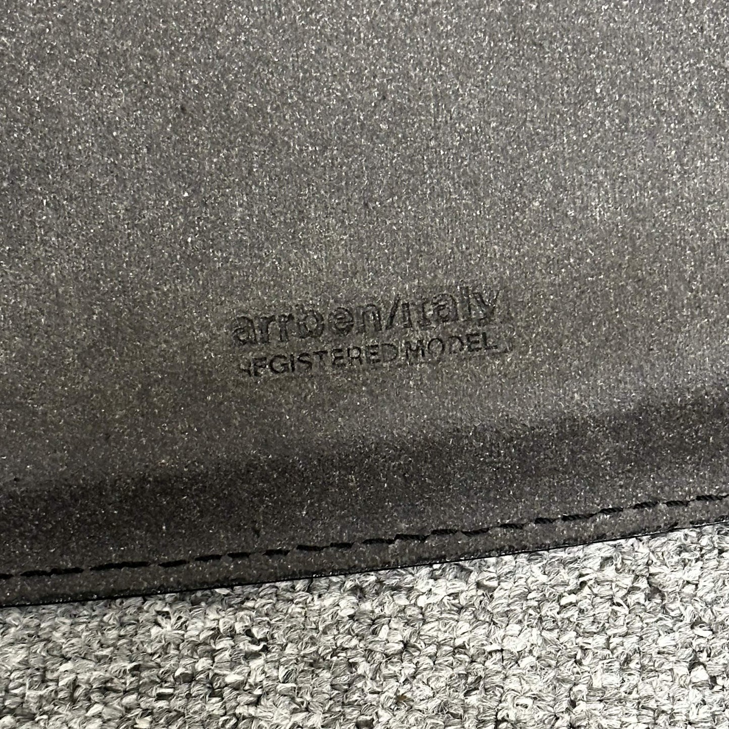 Close-up of Arrben Italy Linda black leather chair with logo embossed on leather seat.