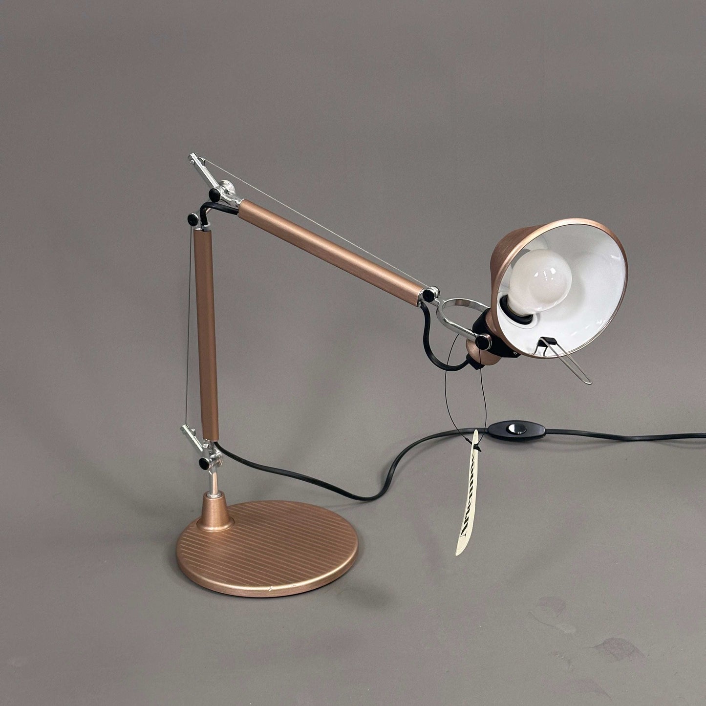 Artemide Tolomeo Micro copper adjustable desk lamp with included bulb on gray background
