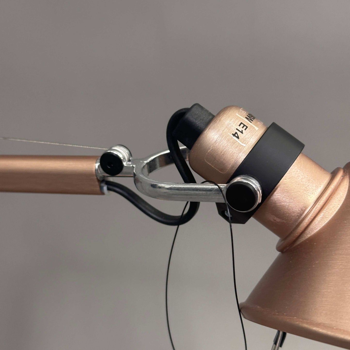 Close-up of copper Artemide Tolomeo Micro adjustable desk lamp head and arm.
