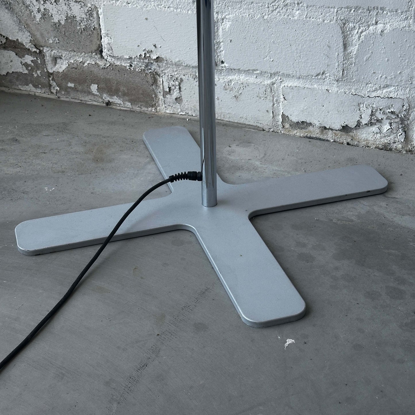 Belux Koi Stehlampe chromer Standfuß mit Stromkabel vor weißer Backsteinwand
