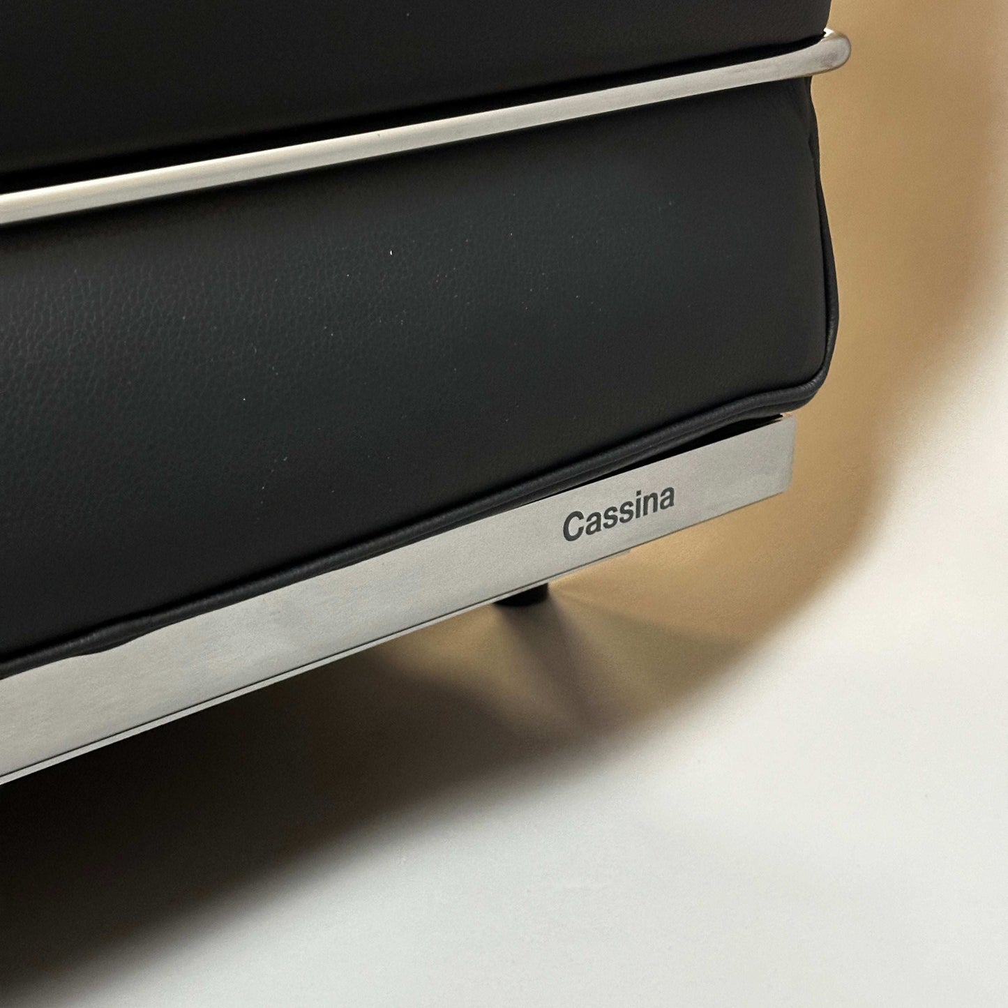 Close-up of Cassina LC2 black leather 2-seater sofa frame with chrome steel tubing and Cassina branding.
