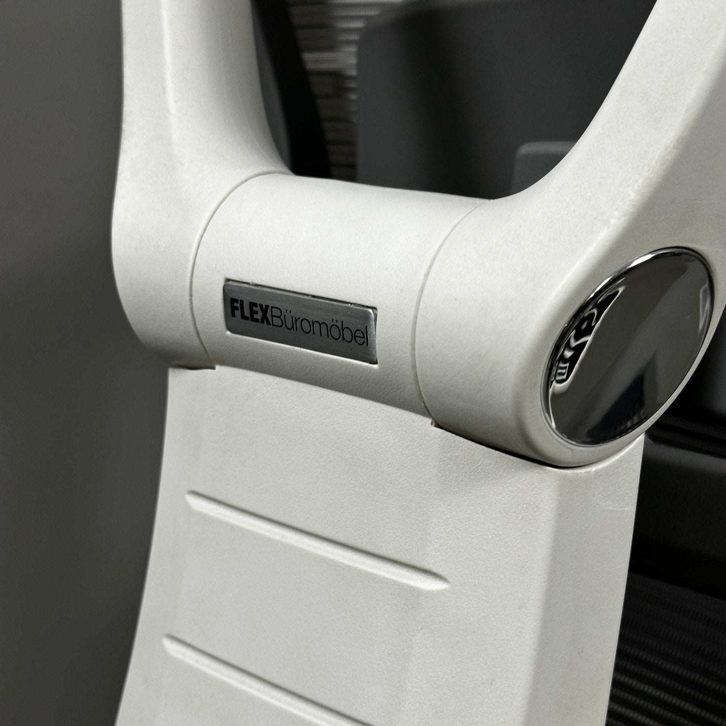 Close-up of white aluminum frame of ergonomic office chair with FLEX Büromöbel logo