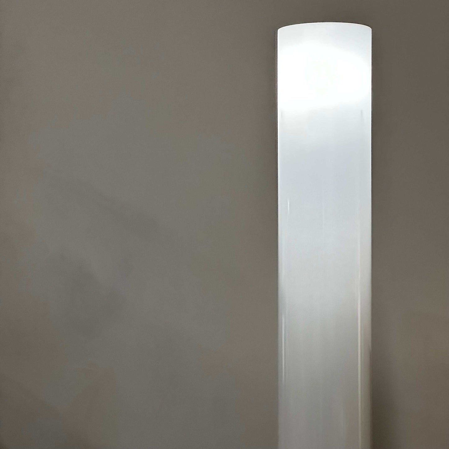 Tall white modern FLOS Stylos Stehlampe floor lamp with sleek minimalist design and diffuse light on a gray background