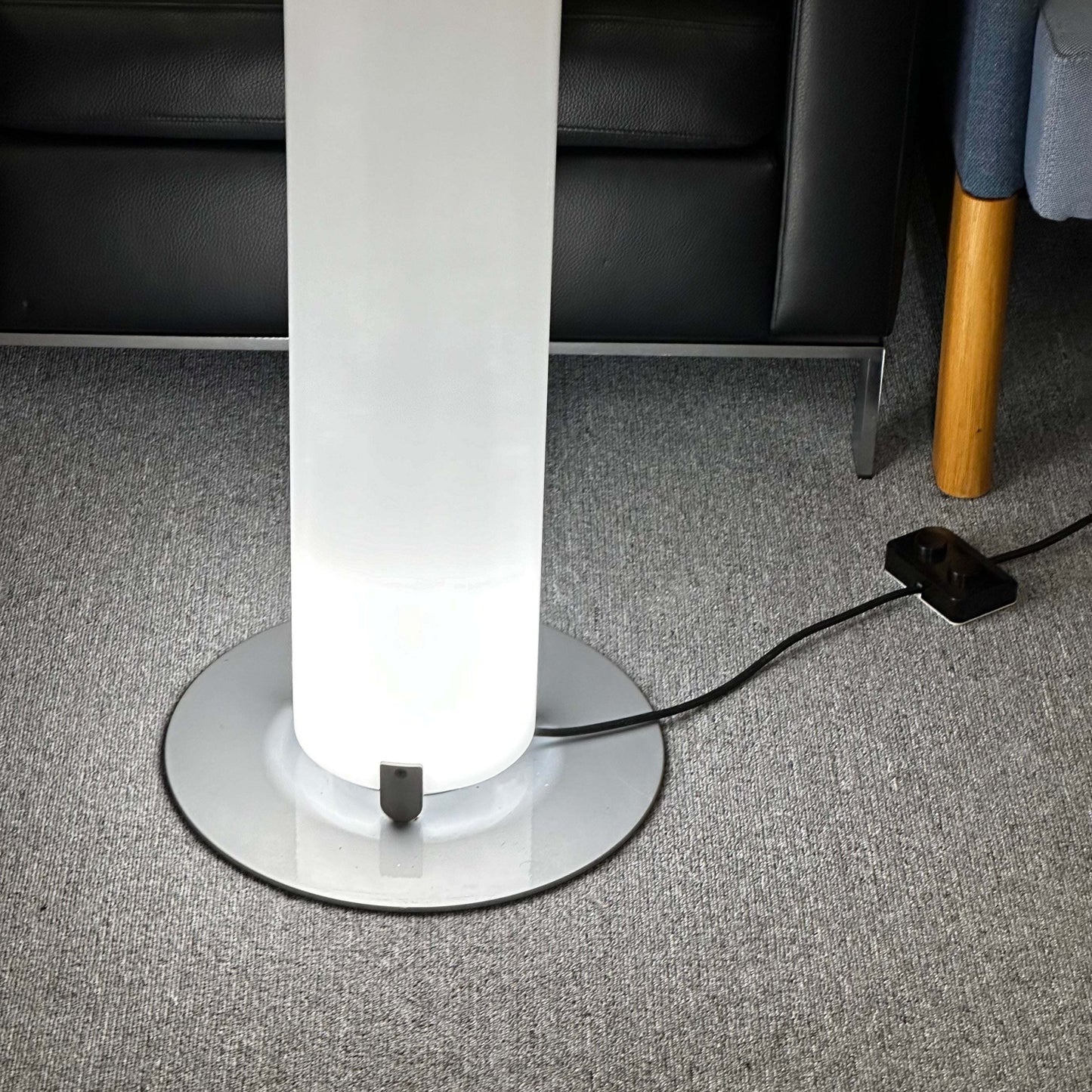 FLOS Stylos Stehlampe modern floor lamp with sleek white cylindrical shade and round base on carpeted floor