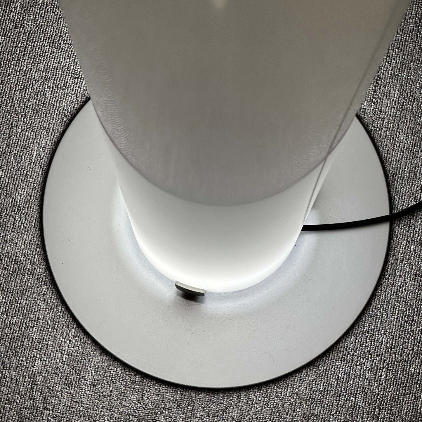 FLOS Stylos Stehlampe modern floor lamp with sleek white base and diffused lighting on textured carpet