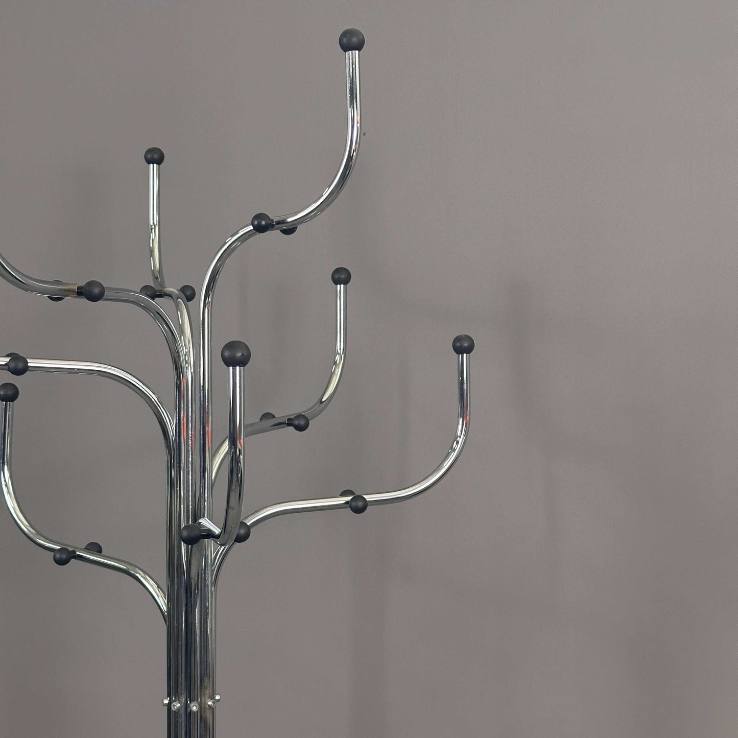 Silver Fritz Hansen Coat Tree with multiple curved hooks and black rounded tips against a gray background