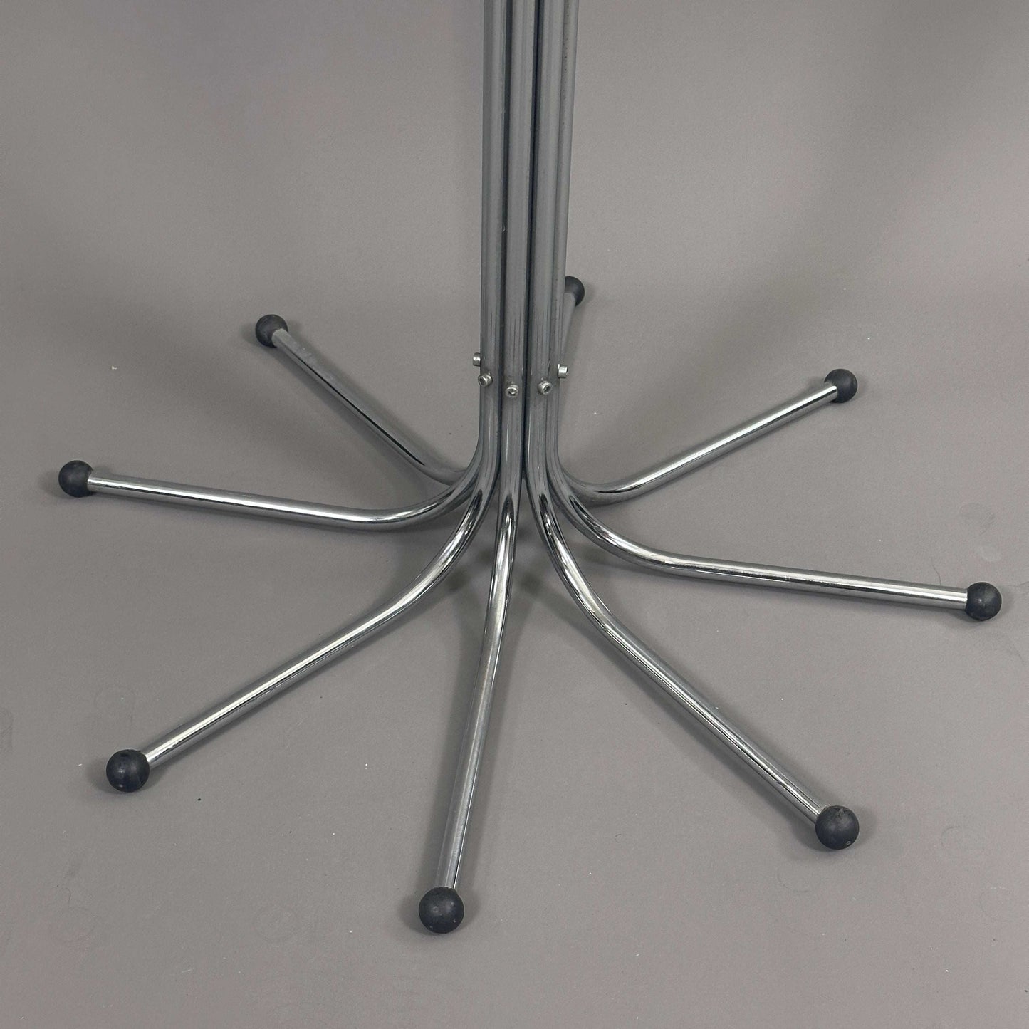 Fritz Hansen Coat Tree silver metal base with multiple arms and black rubber tips on gray background