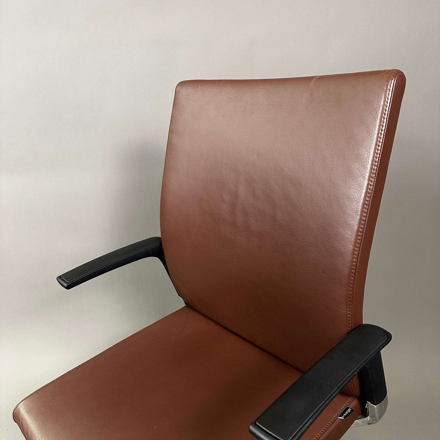 Brown leather Girsberger Camiro work&meet office chair with black armrests and adjustable seating