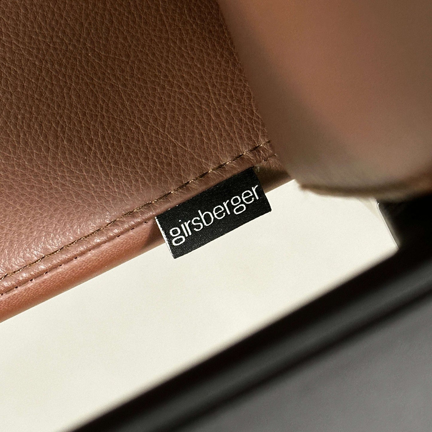 Close-up of brown leather upholstery with Girsberger label on Girsberger Camiro work&meet chair