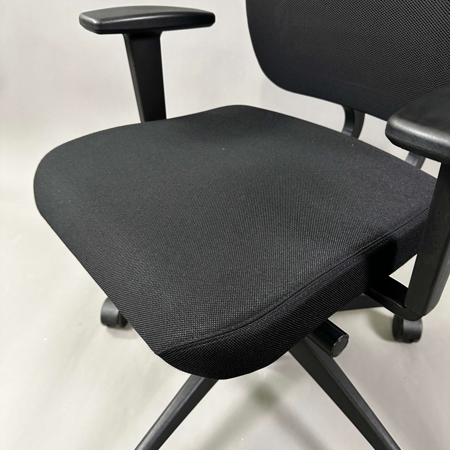 Girsberger Reflex ergonomic office chair with black fabric seat and mesh backrest, adjustable armrests, and synchronized tilt mechanism