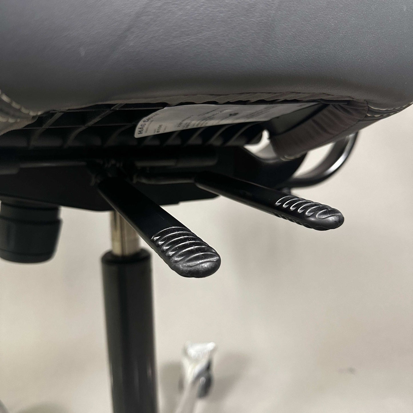 Detailaufnahme der Hebel des HAG Capisco 8107 Schreibtischstuhls mit grauem Soft Leder und poliertem Aluminiumgestell