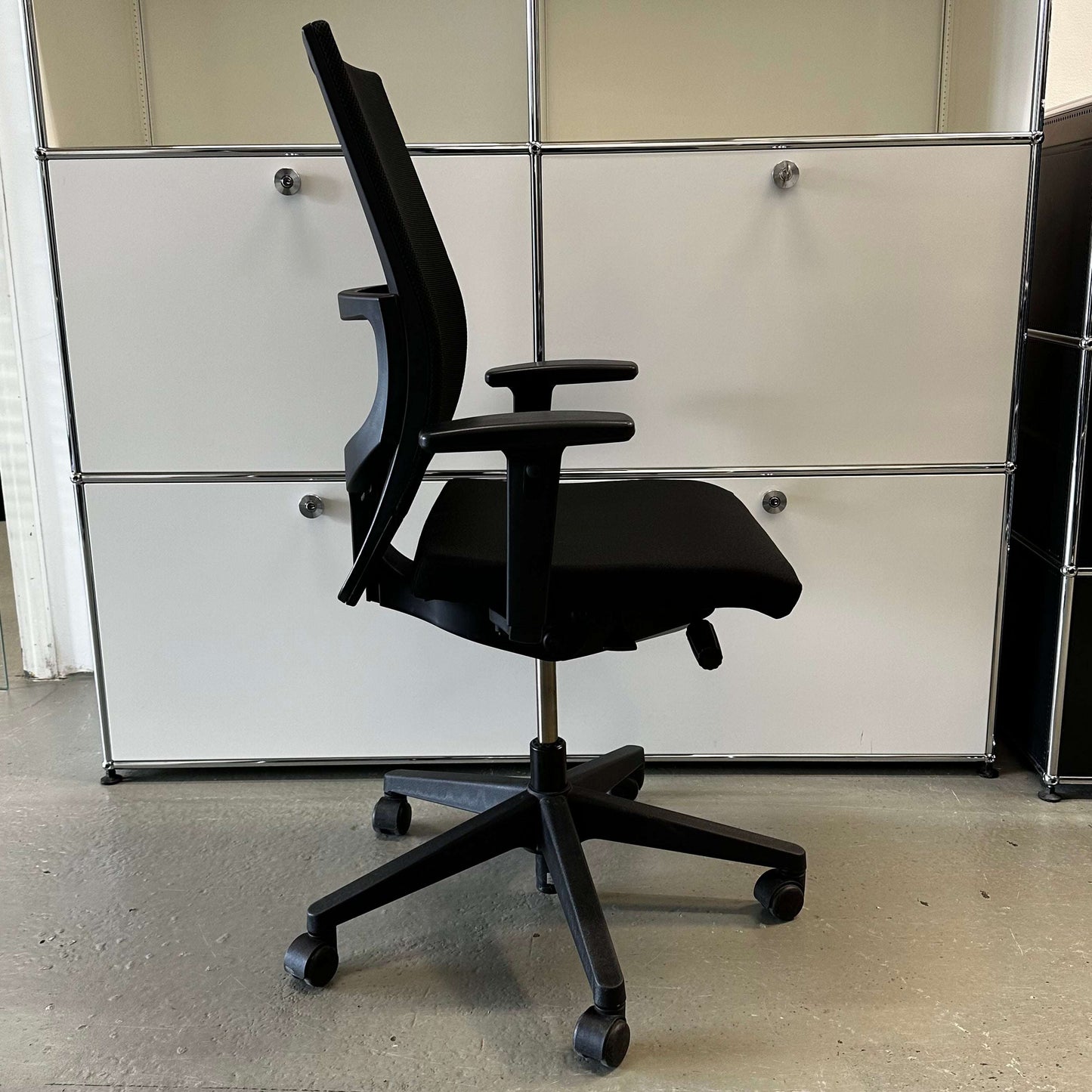 Haworth Comforto 39 black office chair with mesh back, adjustable armrests, height-adjustable seat, and black base with caster wheels