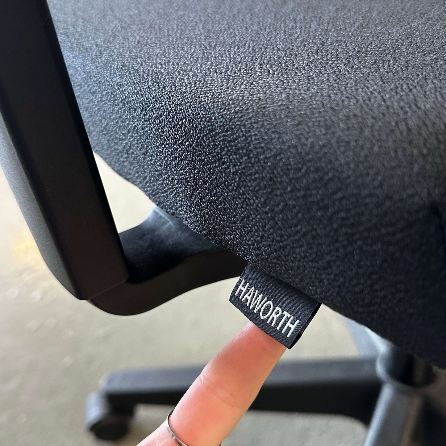 Close-up of black Haworth Comforto 39 office chair fabric with adjustable features and logo tag
