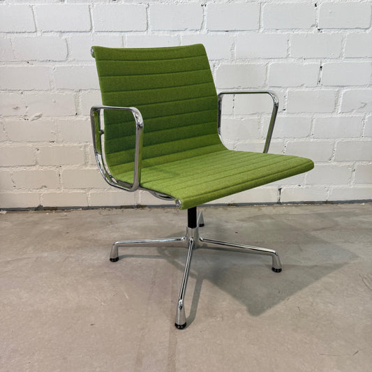 Vitra EA 108 Hopsak swivel chair in green fabric with chrome frame against white brick wall