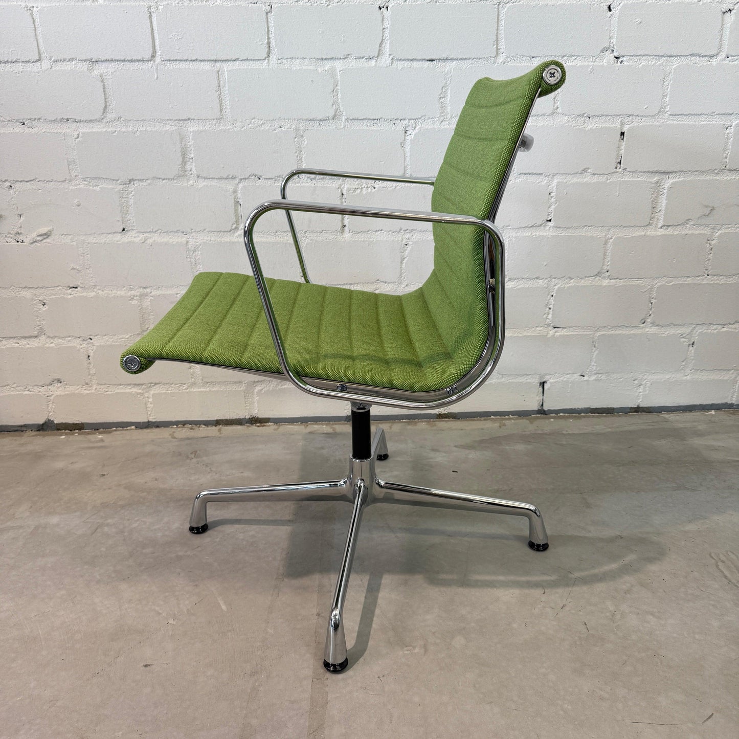 Vitra EA 108 Hopsak swivel chair in green Hopsak fabric with chrome frame against white brick wall
