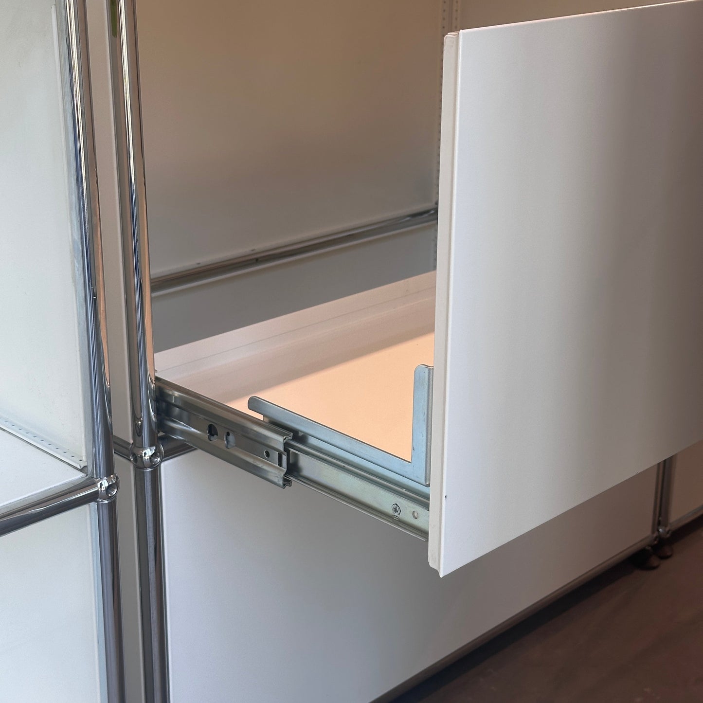 USM Haller white sideboard with two drawers partially open showing metal sliding mechanism