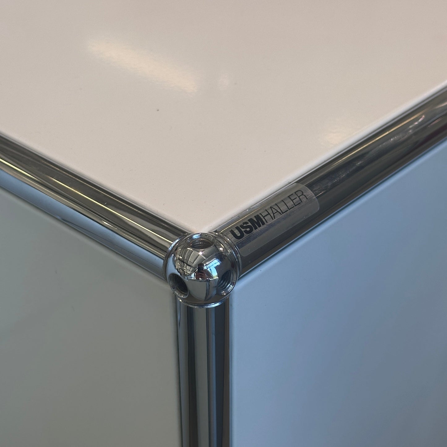 Close-up of white USM Haller Sideboard 1x2 corner with chrome frame and logo plate