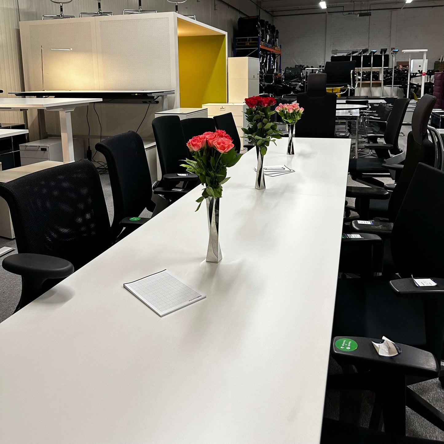 white and silver 4 meter long Konferenztisch 4m x 80 cm with black chairs and decorative flower vases in modern office setting