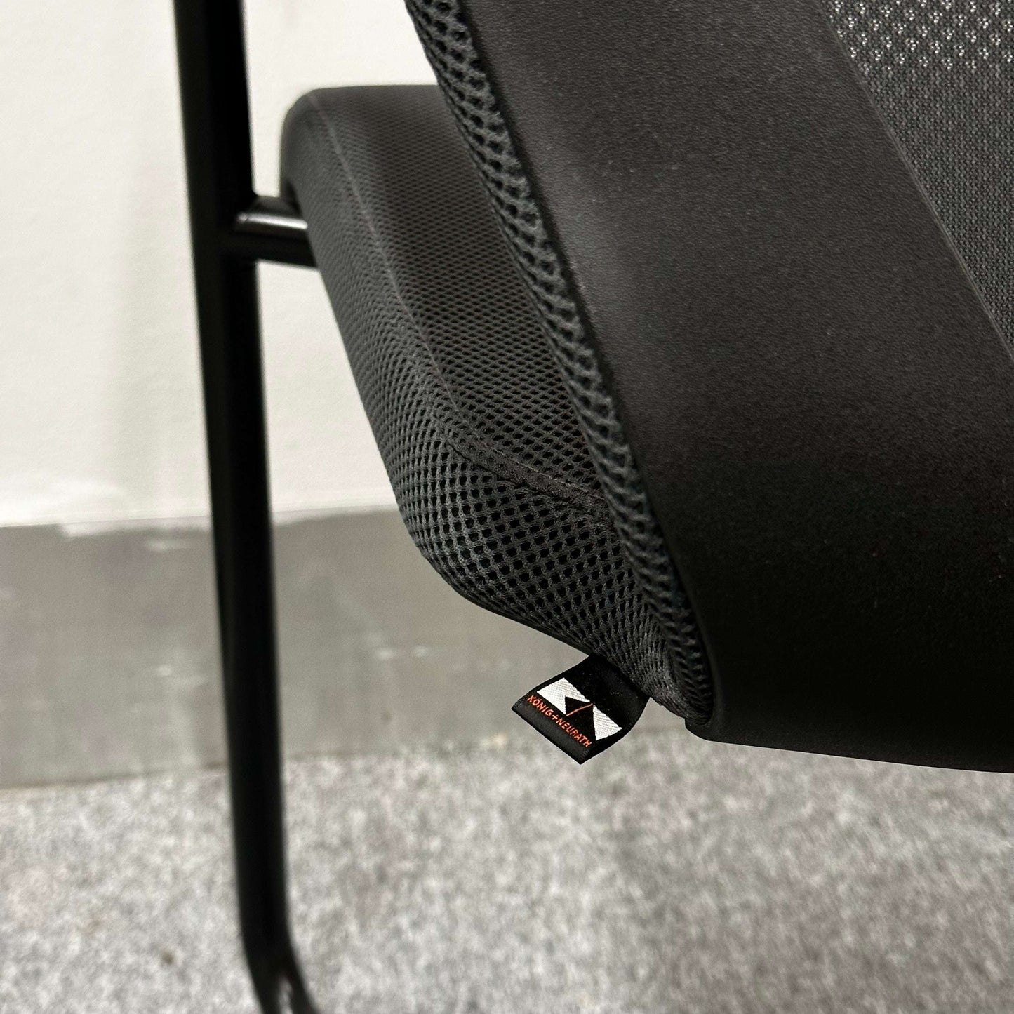 Close-up of König+Neurath Konferenzstuhl ergonomic conference chair seat with black mesh fabric and modern design.