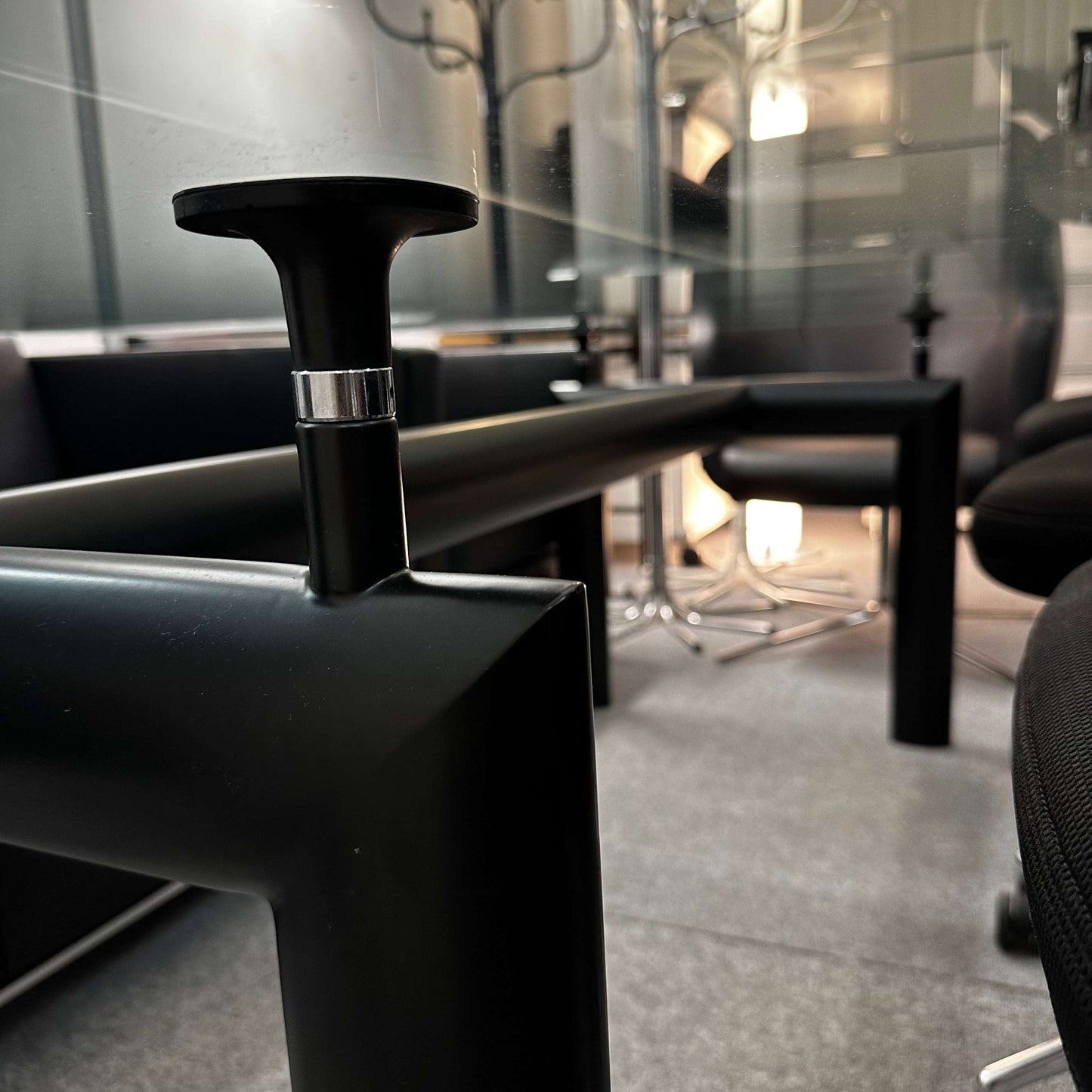 Close-up of black adjustable leg and glass tabletop of LC6 Tisch replica with modern design details