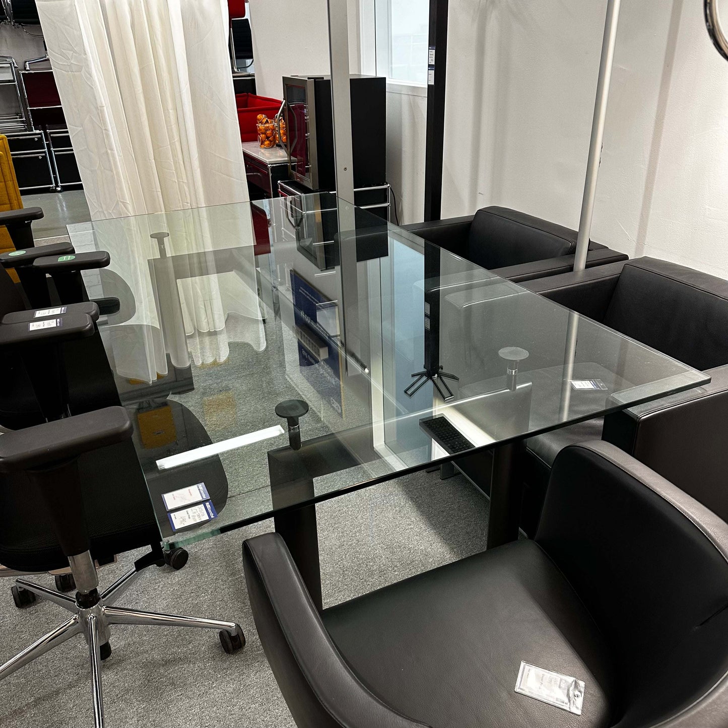 Adjustable height LC6 Tisch replica with glass tabletop and black chairs around in office setting