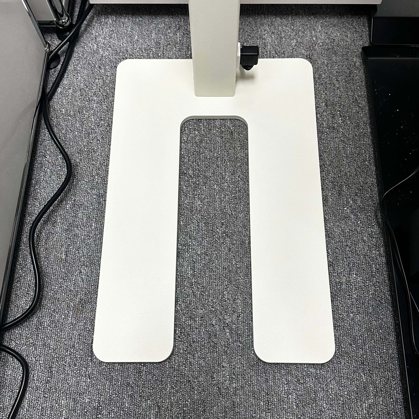 White rectangular base of Lenorad LED Stehlampe floor lamp on gray carpet with power cords nearby