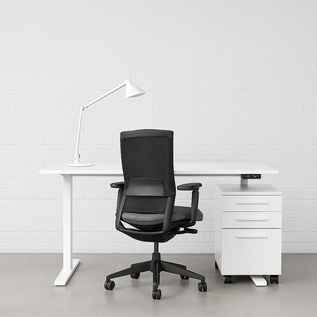 White EHV-1 elektrisch höhenverstellbarer Schreibtisch mit weißer Tischplatte, schwarzem Bürostuhl, Schreibtischlampe und weißem Rollcontainer vor weißer Backsteinwand.
