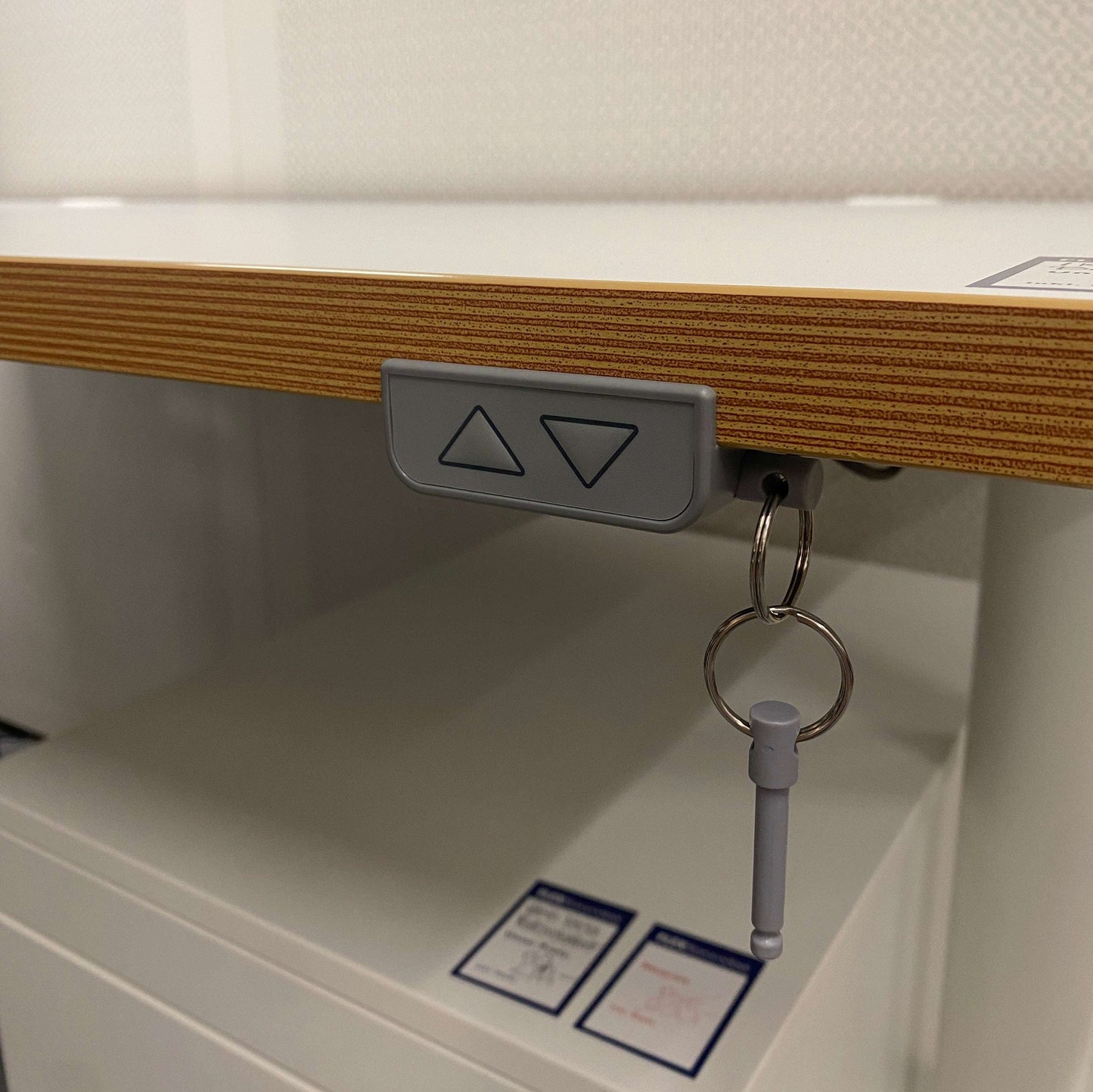 Close-up of electric height adjustment control on Ikea Bekant white 160x80cm desk with multiplex edge and keychain accessory.