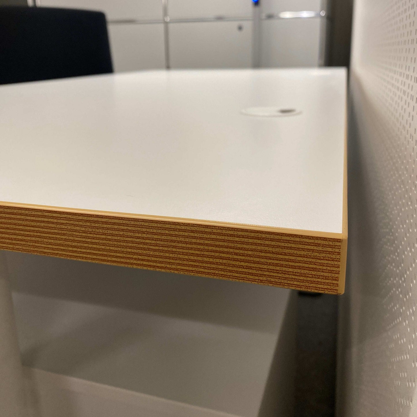 Close-up of a white 160x80cm electrically height-adjustable desk with multiplex edge and cable management system