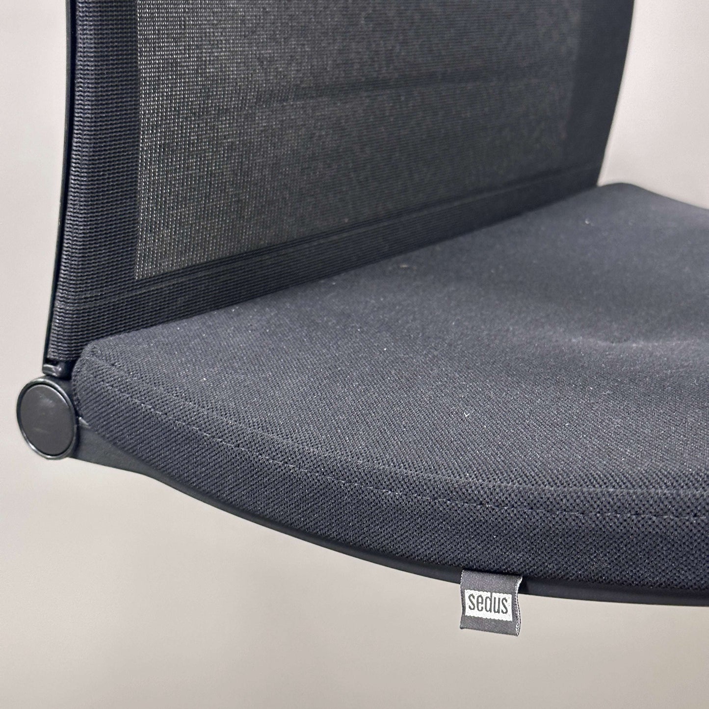 Close-up of Sedus OpenUp Freischwinger chair with black mesh backrest and cushioned seat on chrome frame