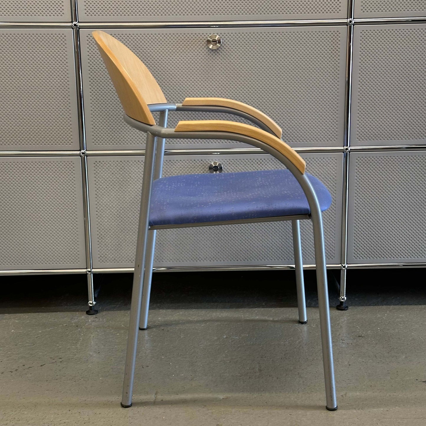 Stackable chair with beech wood backrest, blue fabric seat, and silver metal frame