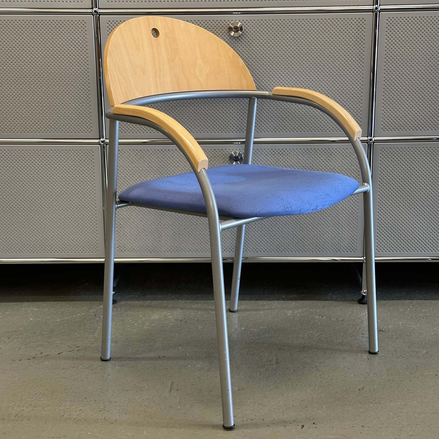 Stackable chair with beech wood backrest, blue fabric seat, and silver metal frame details
