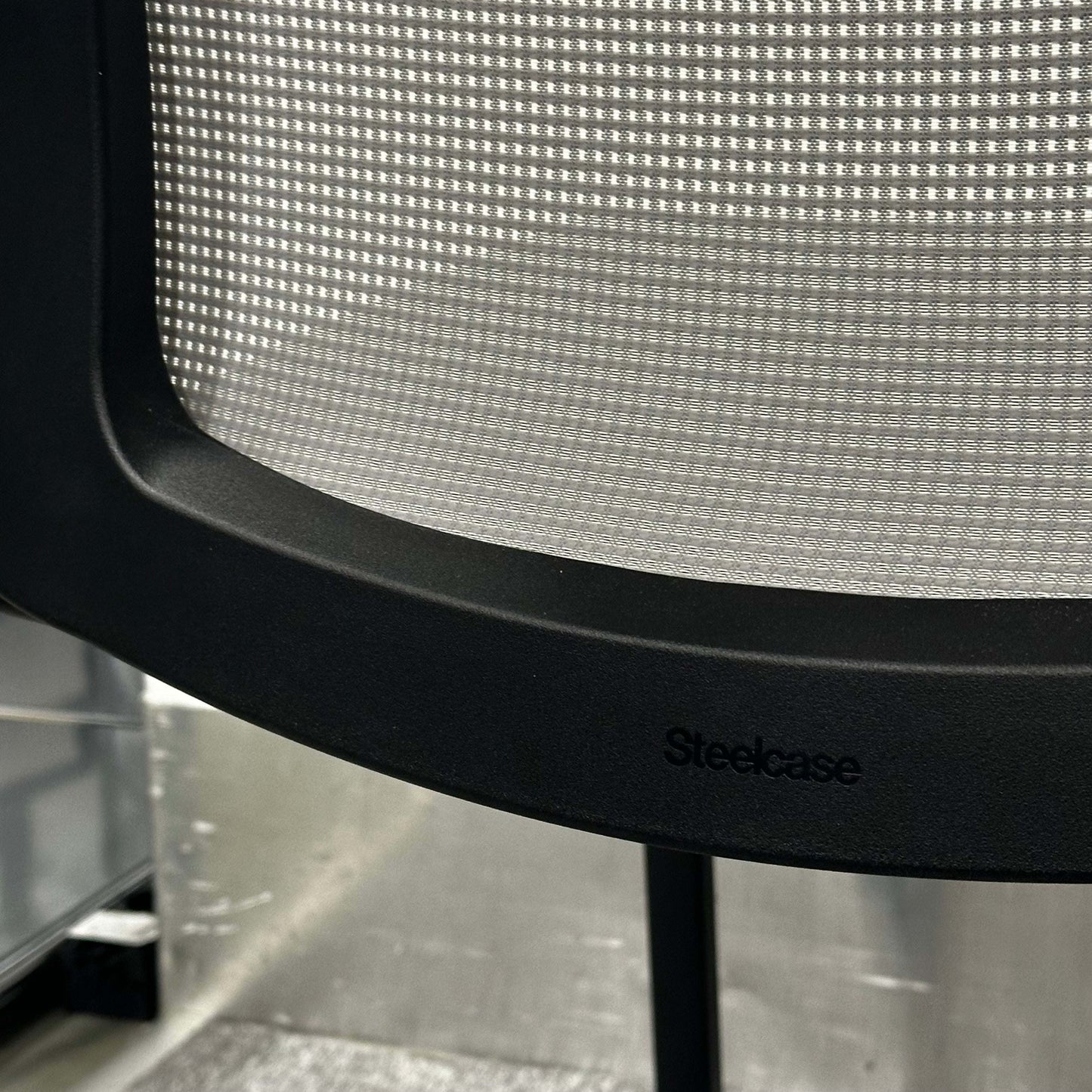 Close-up of Steelcase Eastside Freischwinger chair mesh backrest with black frame and logo