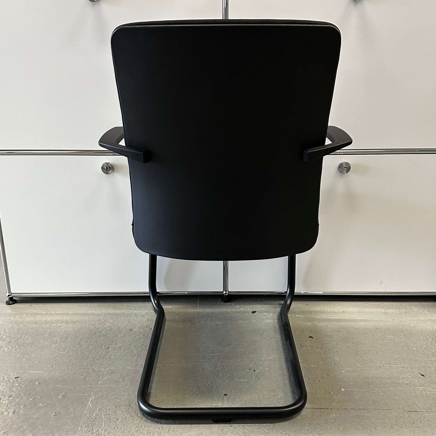 Steelcase Northside black padded office meeting chair with black frame and cantilever base viewed from back