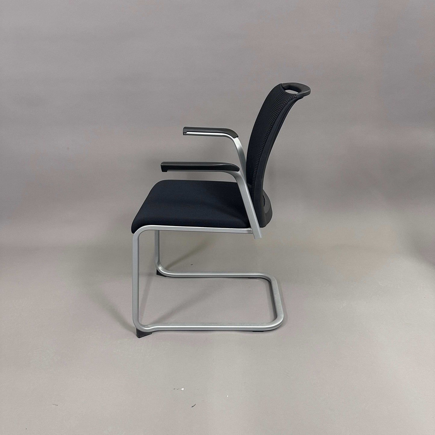 Steelcase Northside black mesh back meeting chair with silver frame and armrests, stackable office seating.