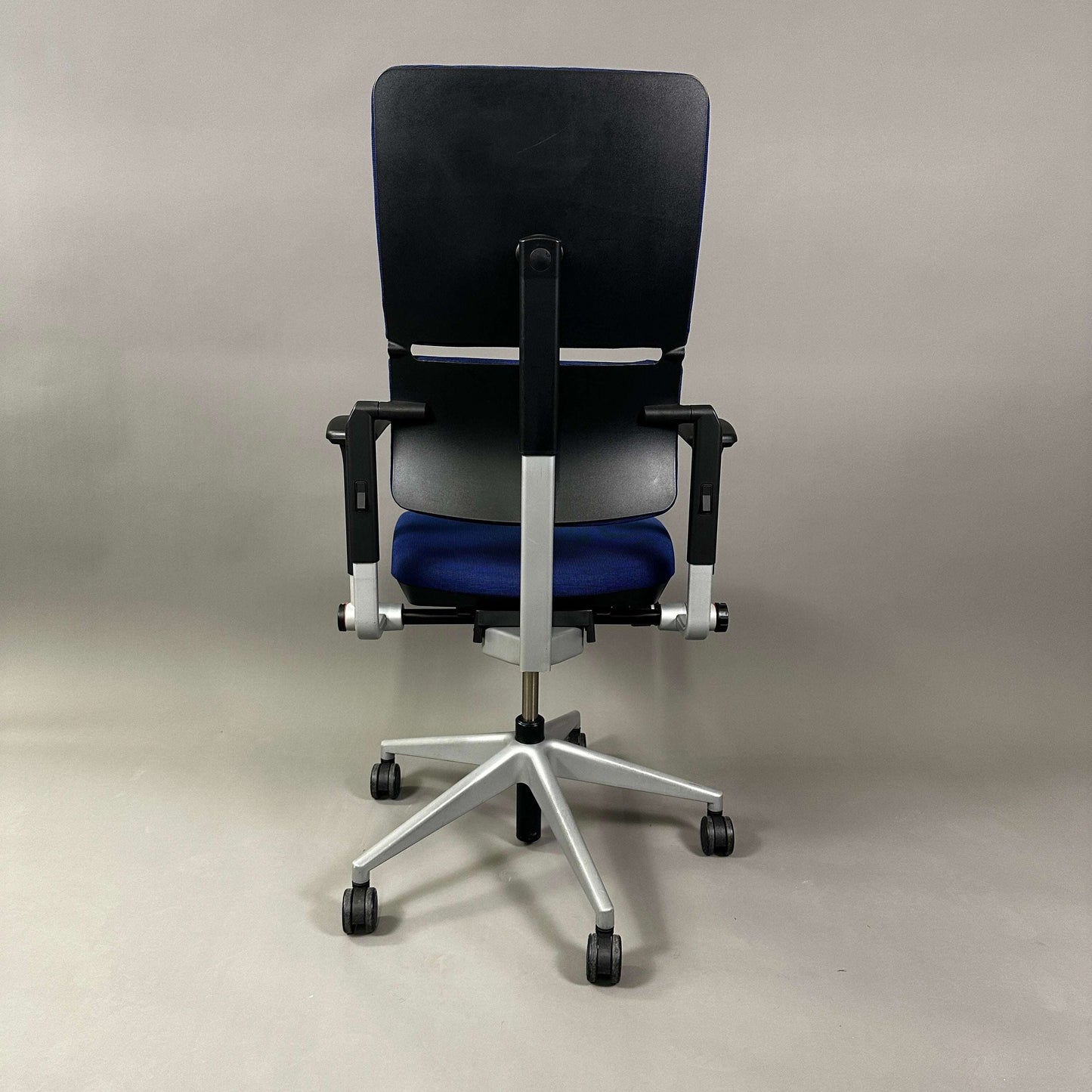 Ergonomic Steelcase Please office chair in blue with adjustable armrests, lumbar support, and silver metal frame shown from the back.