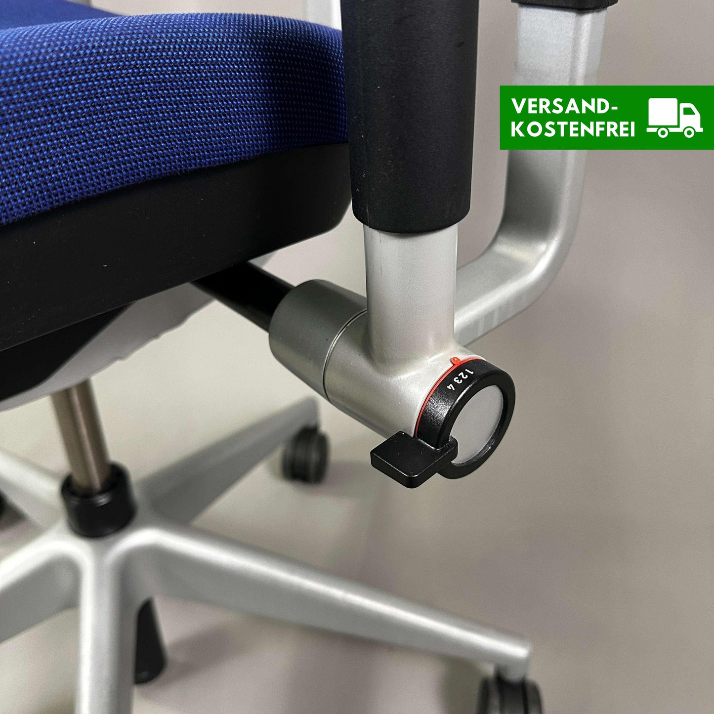 Close-up of adjustment knob on blue Steelcase Please ergonomic office chair with silver metal frame and caster wheels