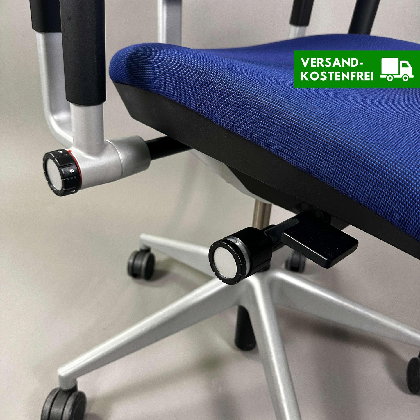 Close-up of the blue Steelcase Please office chair seat with adjustable knobs and silver metal base on casters