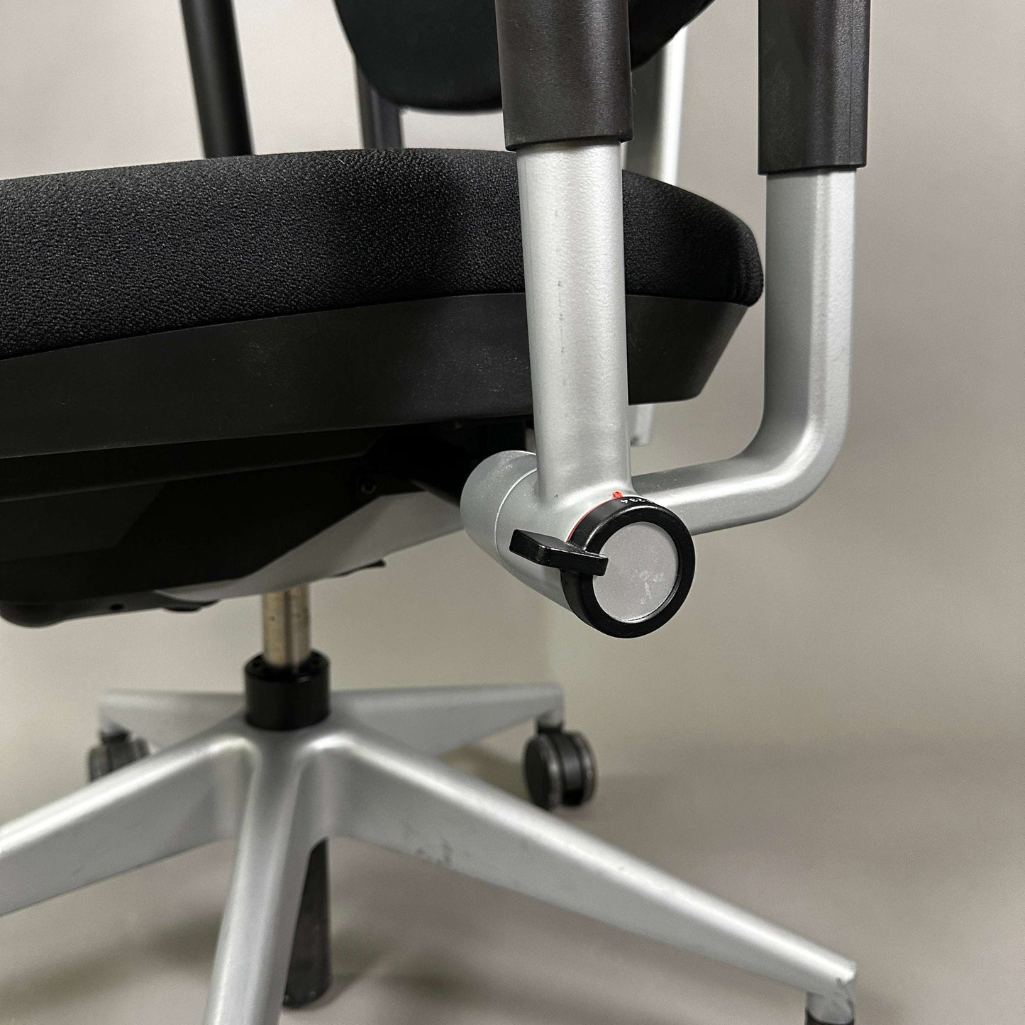 Steelcase Please office chair black fabric with adjustable armrests and silver base close-up of adjustment mechanism