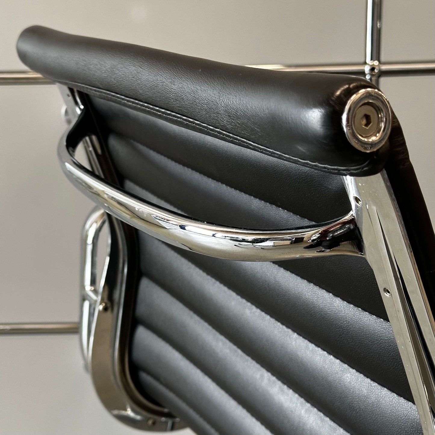 Close-up of black faux leather Stuhl im Vitra EA108 chair replica with chrome frame detailing