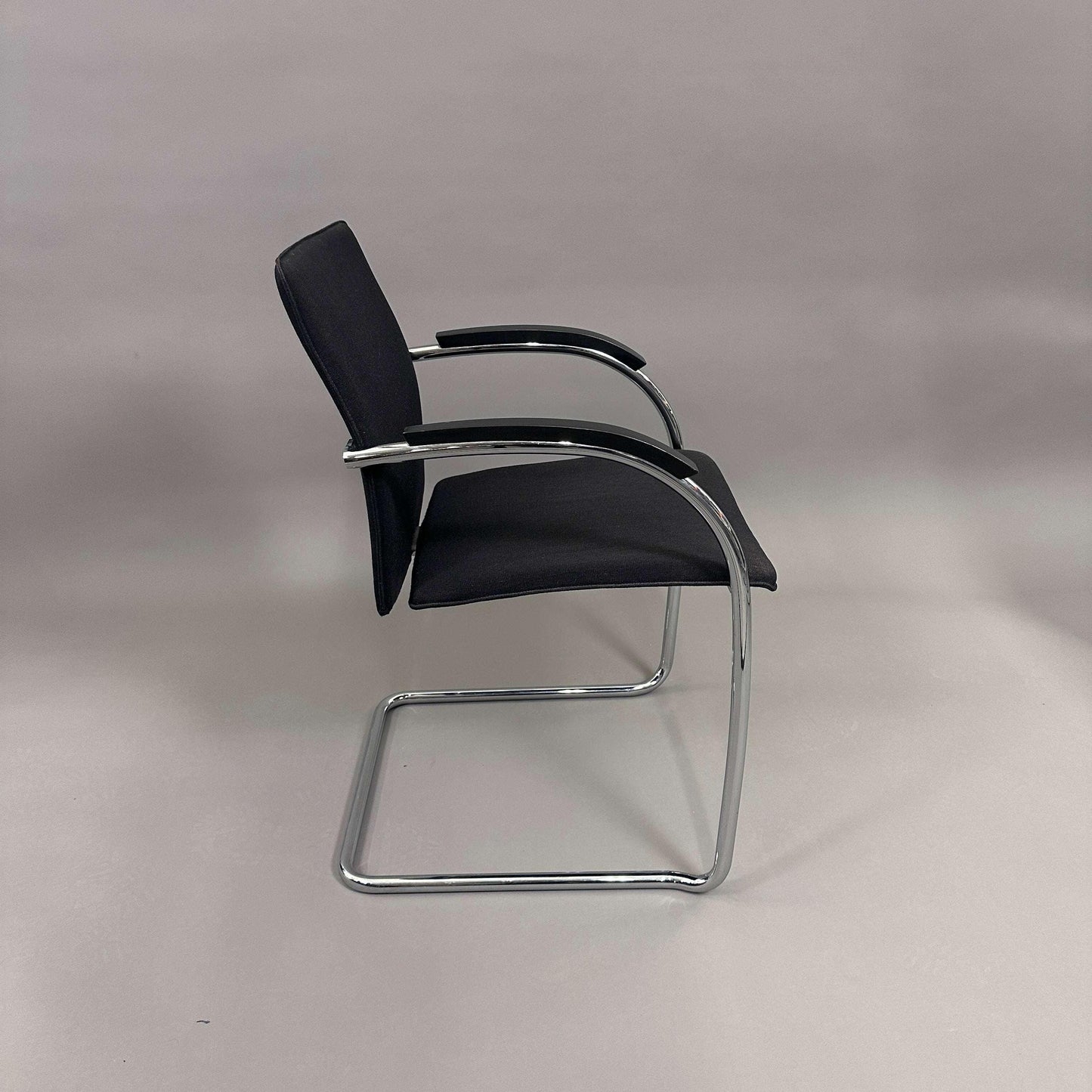 Thonet S78/S79 Freischwinger chair with black upholstery, matte black wooden armrests, and chrome frame viewed from side