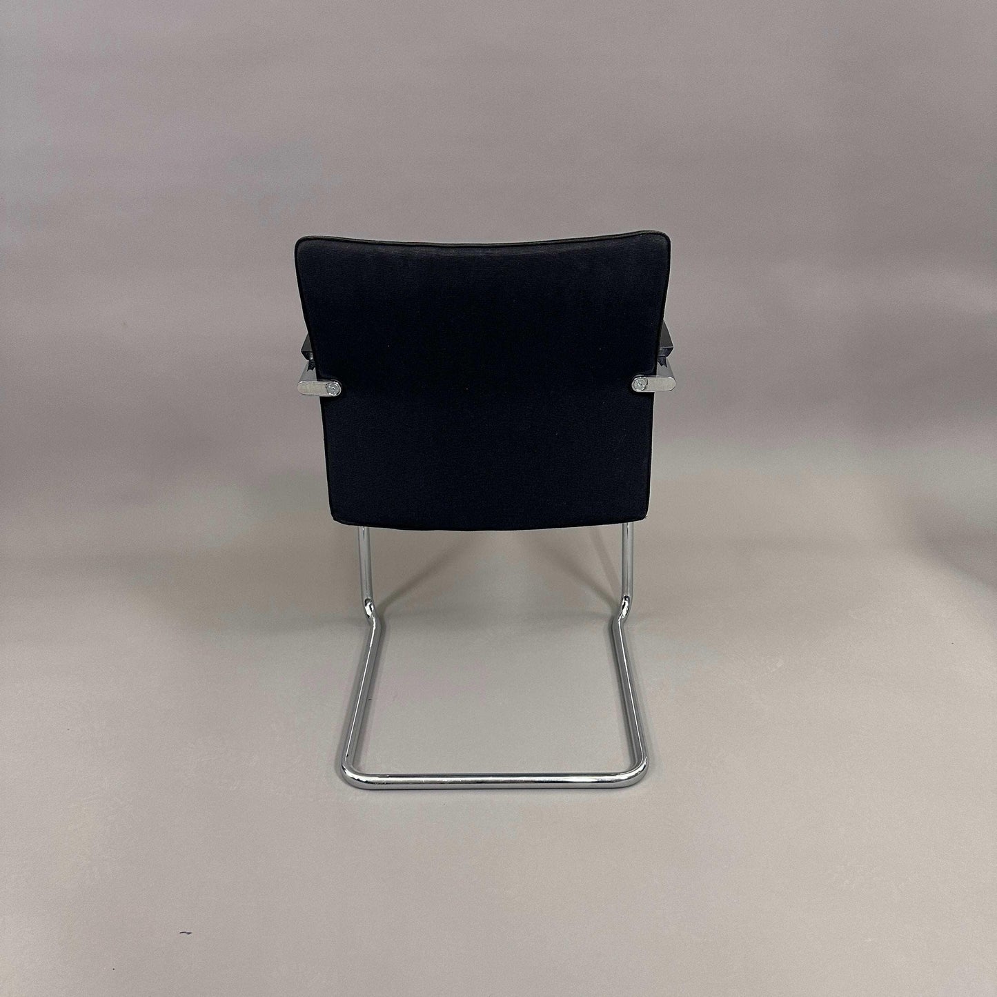 Thonet S78/S79 cantilever chair with black upholstery, matte black wooden armrests, and chrome frame viewed from the back