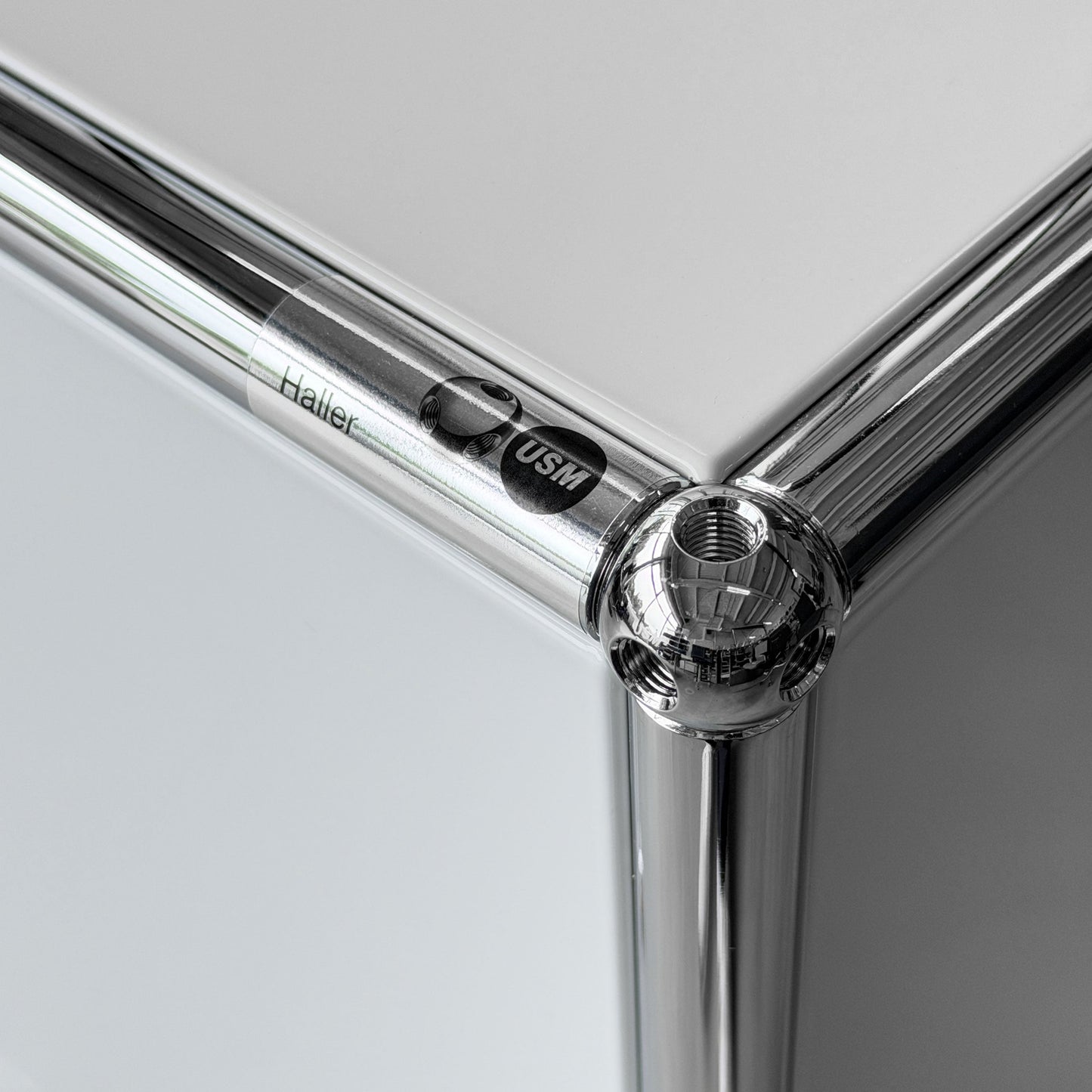 USM Haller 2x2 Sideboard in lichtgrau mit verchromten Stahlrohren und USM Logo.