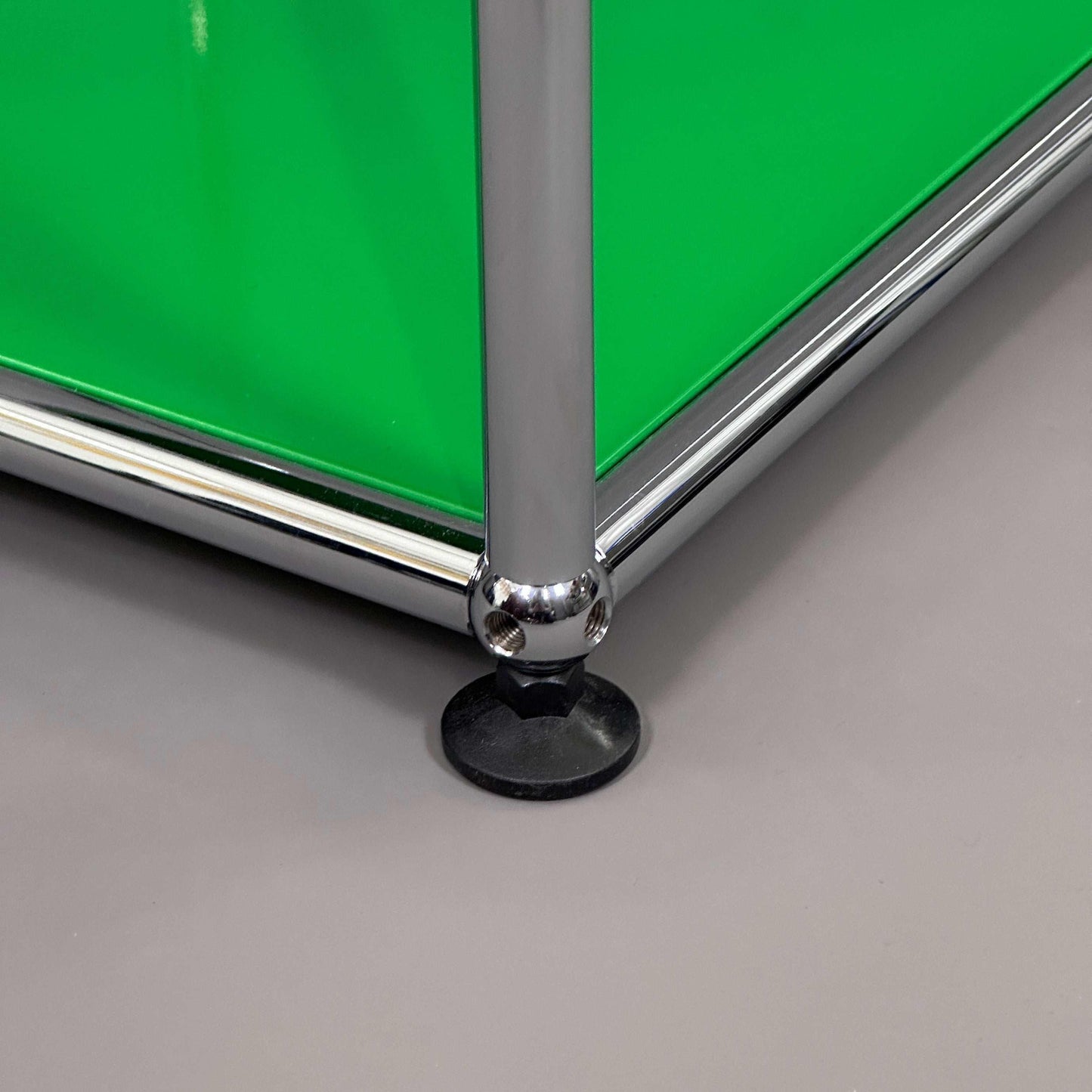 USM Haller Beistelltisch Detail Fuß und grüne Paneele elegante Metallkonstruktion