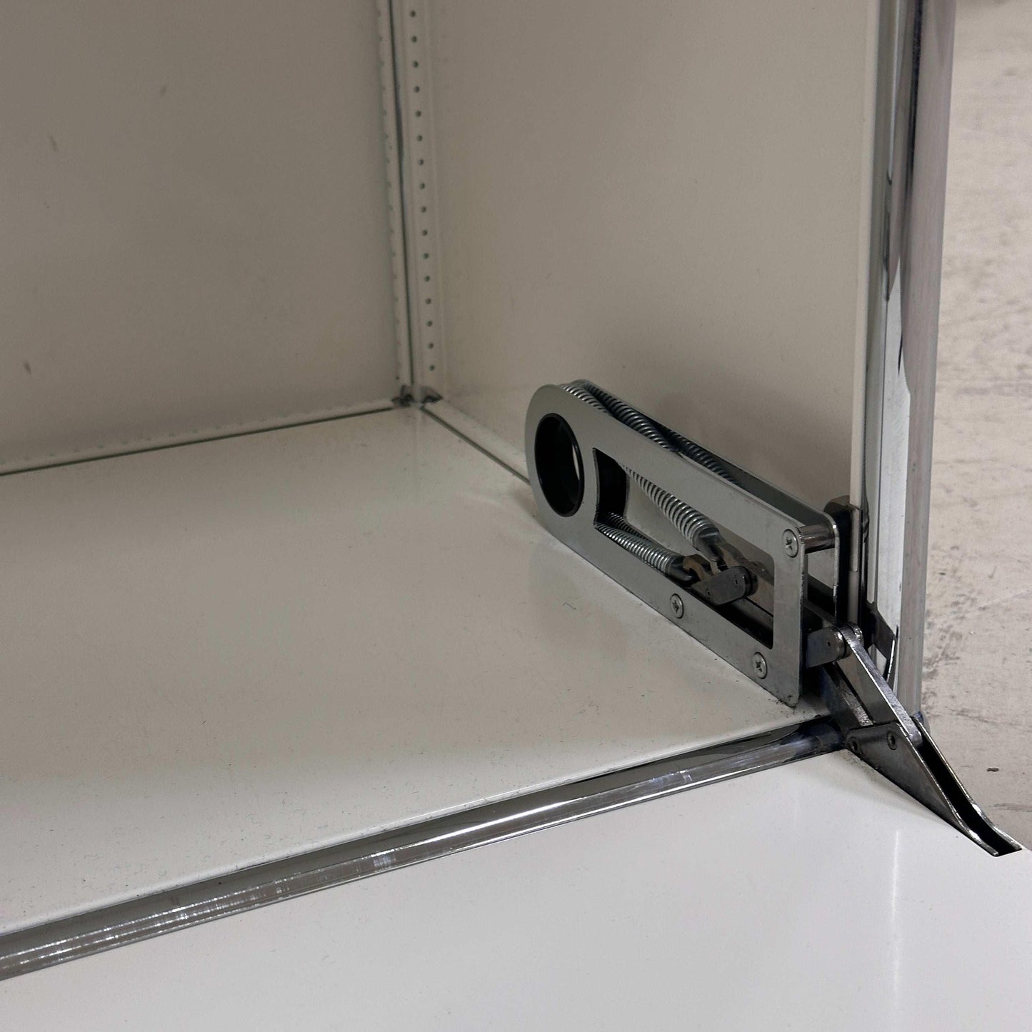 Detailaufnahme der weißen USM Haller Garderobe mit geöffneter Klappe und sichtbarem Scharniermechanismus