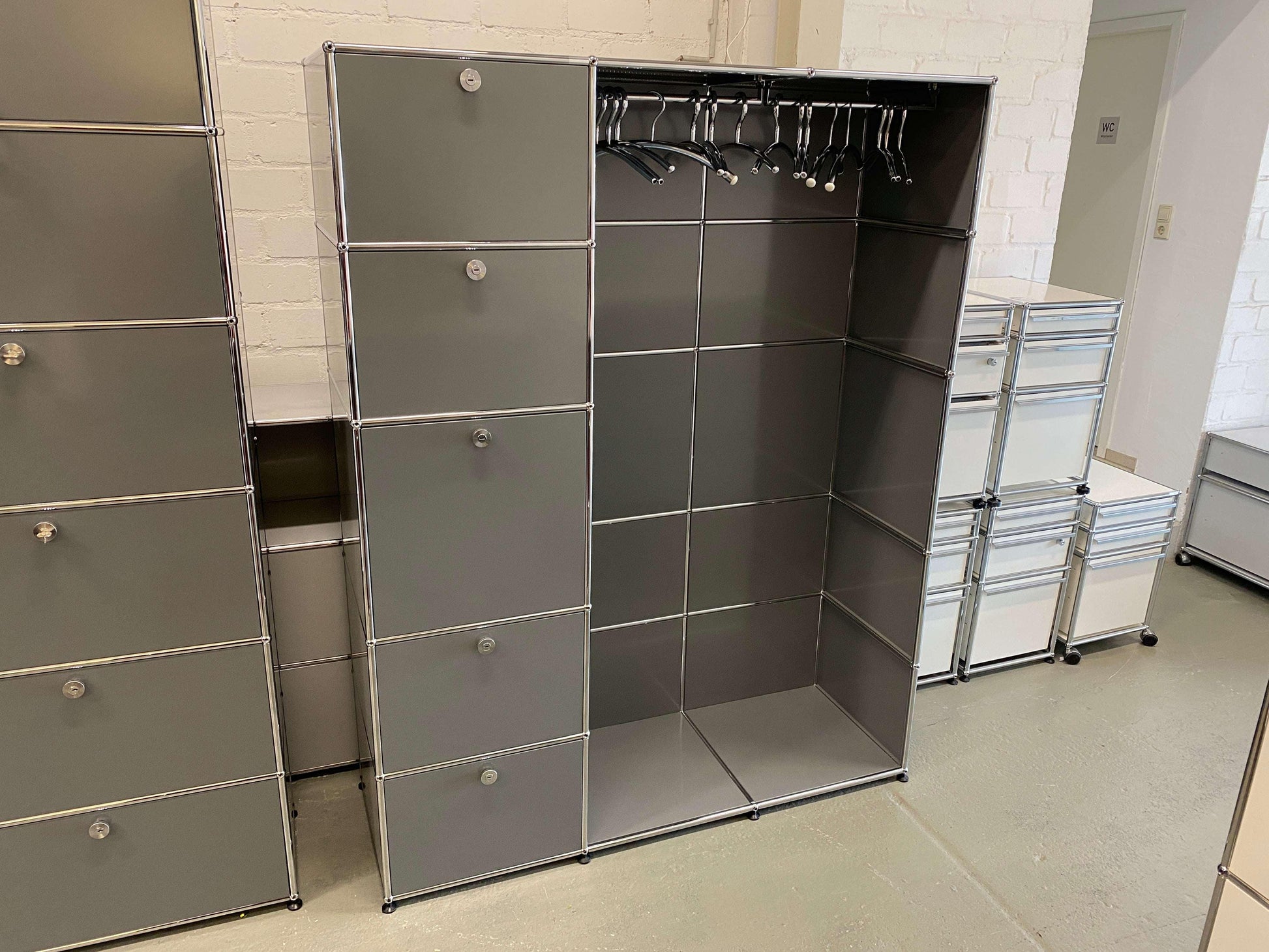 USM Haller Garderobe in medium gray with chrome frame, featuring five compartments and hanging space with clothes hangers for organized entryway storage.