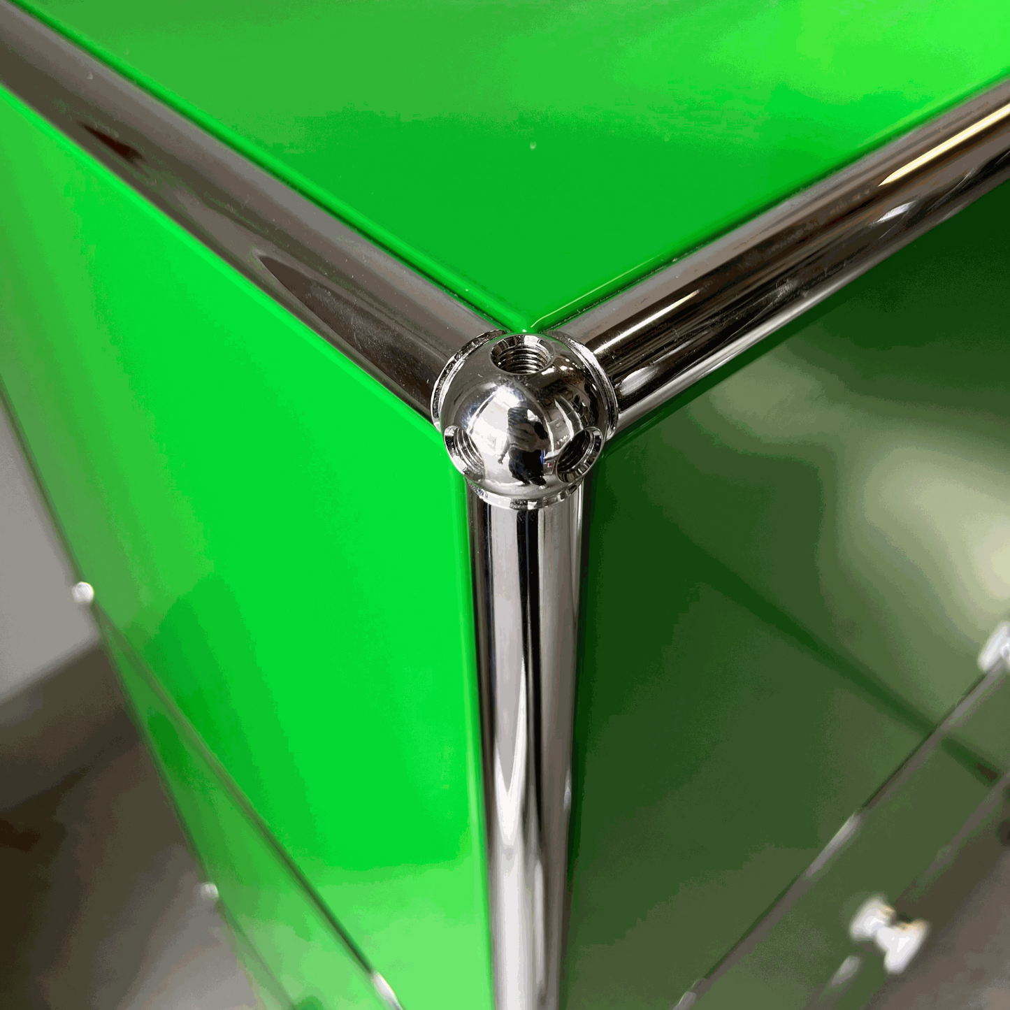 Close-up of green USM Haller Highboard corner with chrome metal frame and screws