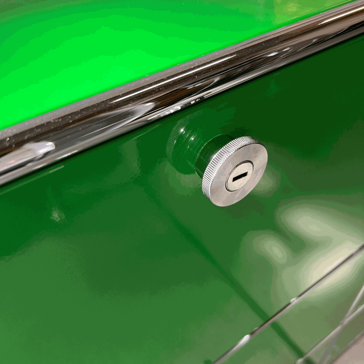 Close-up of a green USM Haller Highboard with chrome lock and soft-close flap detail